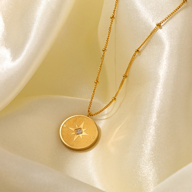 Gold compass star medallion necklace on satin background