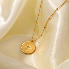 Gold compass star medallion necklace on satin background