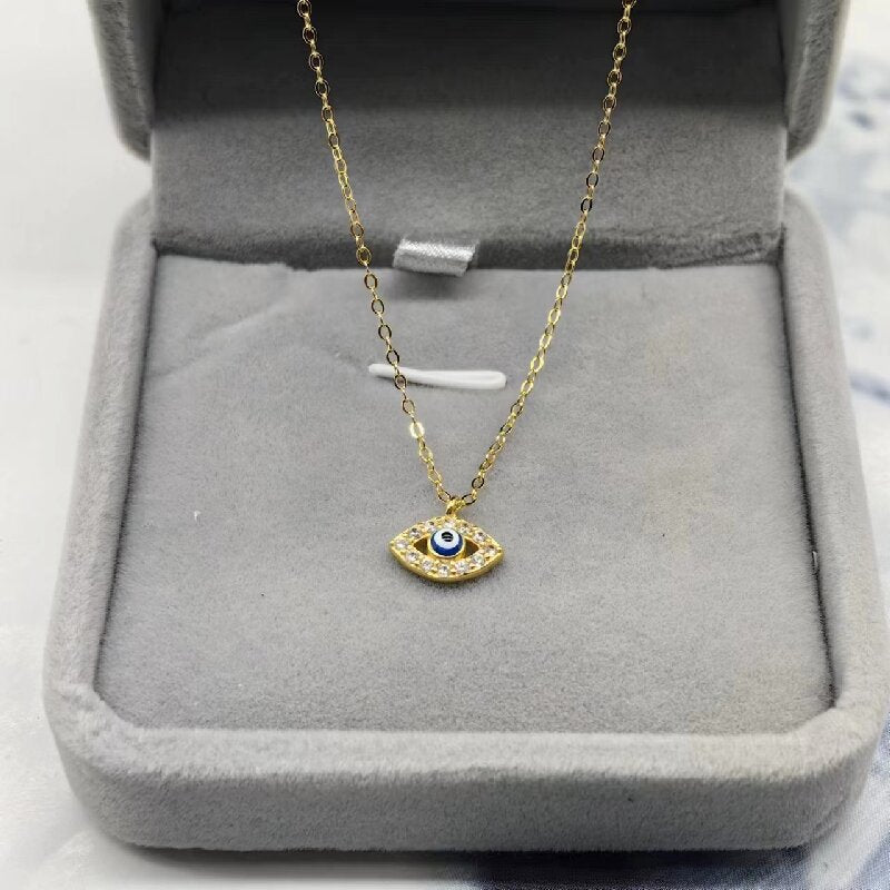 Gold-tone evil eye pendant necklace displayed in a jewelry box