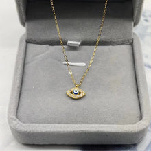 Gold-tone evil eye pendant necklace displayed in a jewelry box