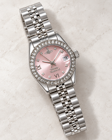 Pink dial bracelet quartz watch showing sparkling bezel, magnified date window and silver-tone steel links