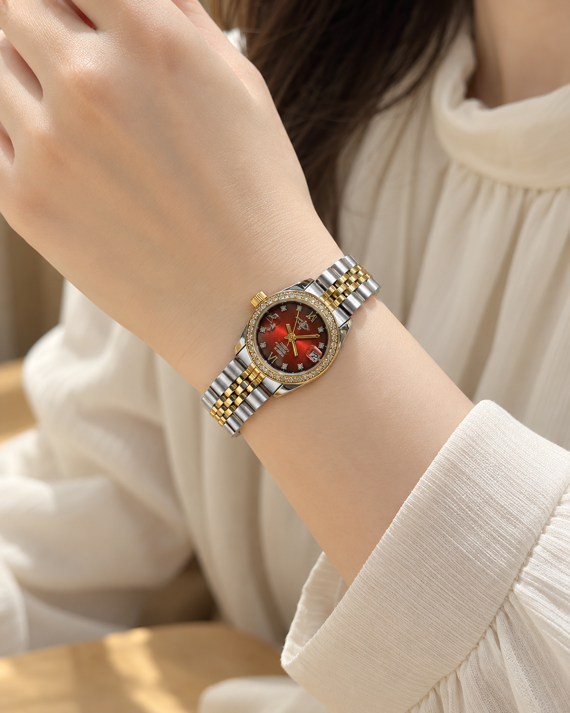 Red dial two-tone quartz bracelet watch worn on an adult wrist with a cream blouse