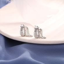 Side view of two silver-tone crystal ear cuffs showing their draped chains