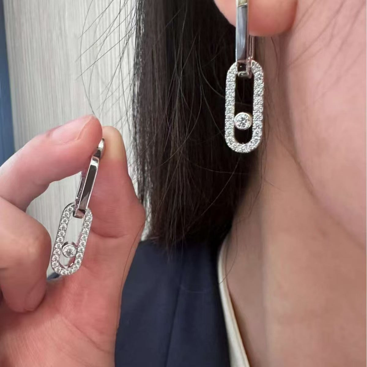 Silver-tone CZ open link earring with sliding stone worn on the ear
