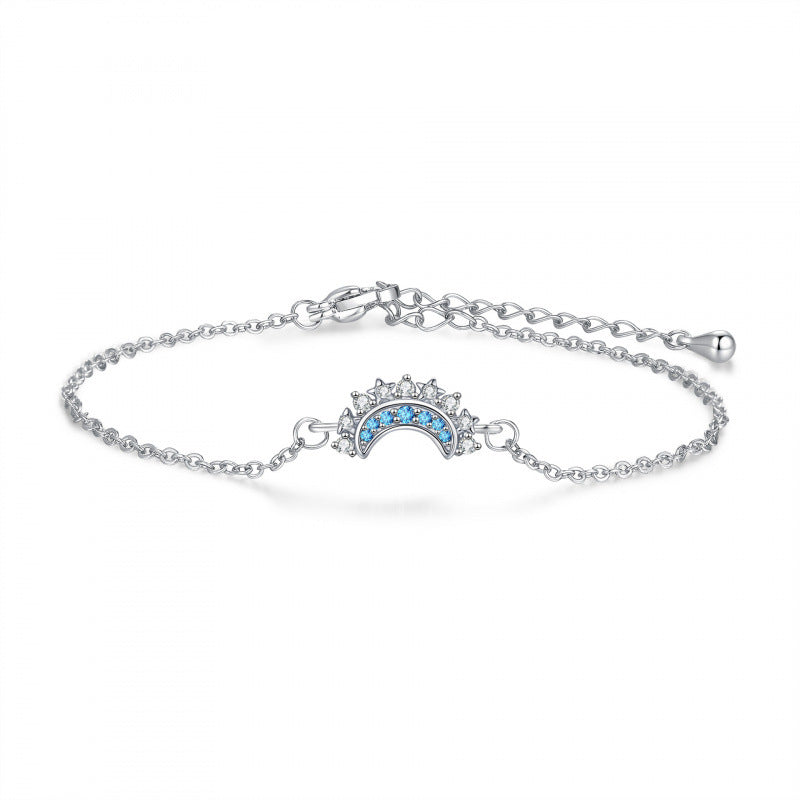 Silver-tone moon motif bracelet with blue zircon accents on a white background