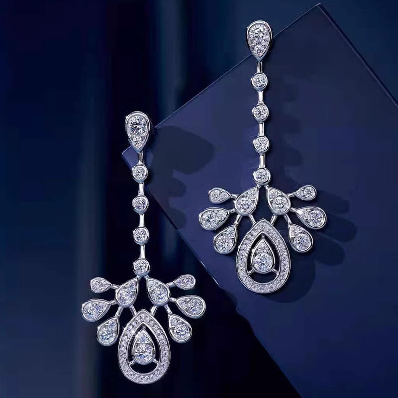 Pair of long silver-tone cubic zirconia chandelier earrings on blue display