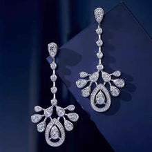 Pair of long silver-tone cubic zirconia chandelier earrings on blue display