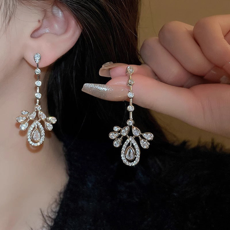 Teardrop CZ chandelier earrings shown on the ear and held by hand