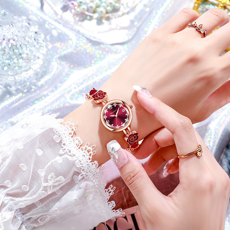 Burgundy camellia bracelet watch worn on a woman's wrist