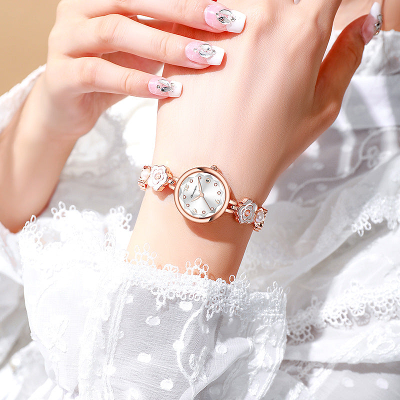 White-dial rose-gold-tone camellia bracelet watch worn on a woman's wrist