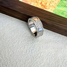 Silver-tone three-row pave circle-motif ring beside a wood display - photo 06