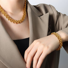 Woman styling a matching gold tone chunky chain necklace and bracelet