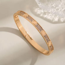 Rose gold tone cubic zirconia screw motif bangle on a neutral display