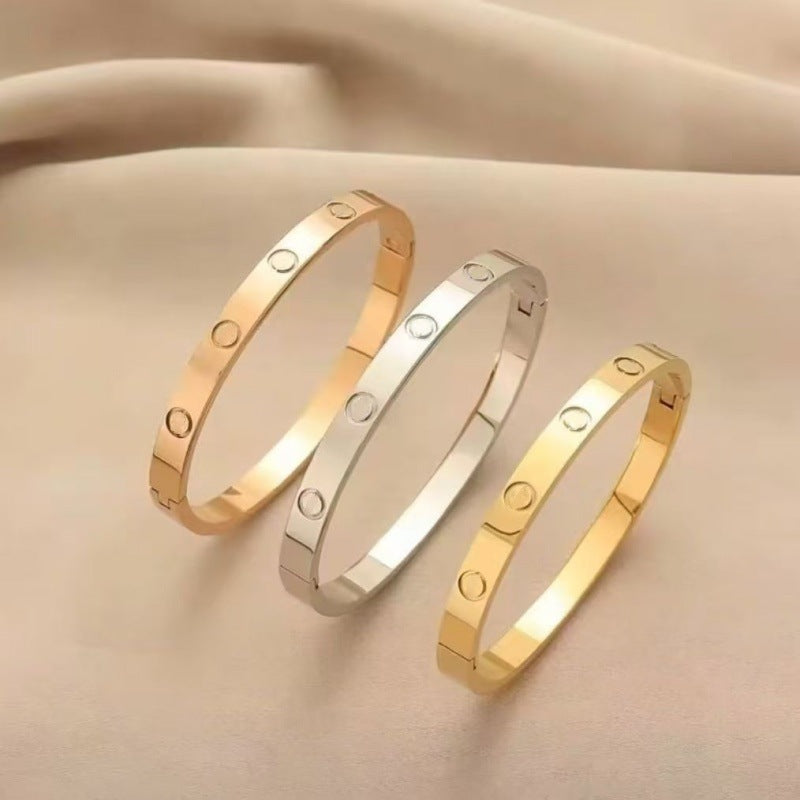 Three plain polished screw motif bangles on neutral fabric