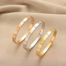 Three plain polished screw motif bangles on neutral fabric