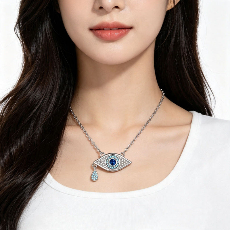 Silver tone blue crystal evil eye pendant necklace styled with a white top
