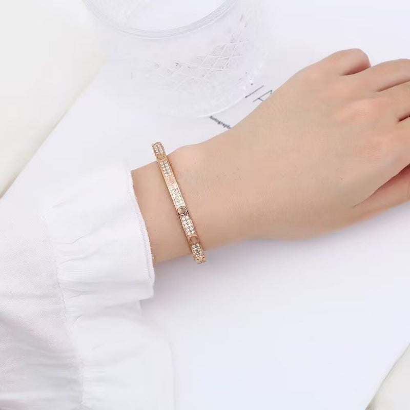 Rose gold tone pave screw motif bangle worn on wrist