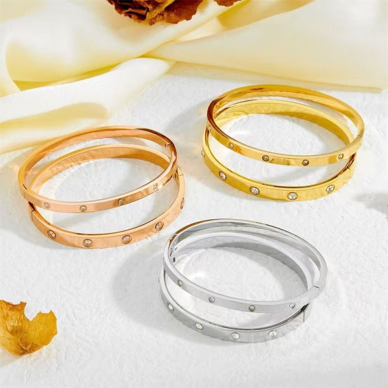 Three slim crystal screw motif bangles in gold, silver and rose gold tones