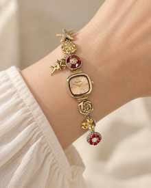 Caramel Khaki rounded-square charm bracelet watch worn on an adult wrist with rose, starfish and cherub details