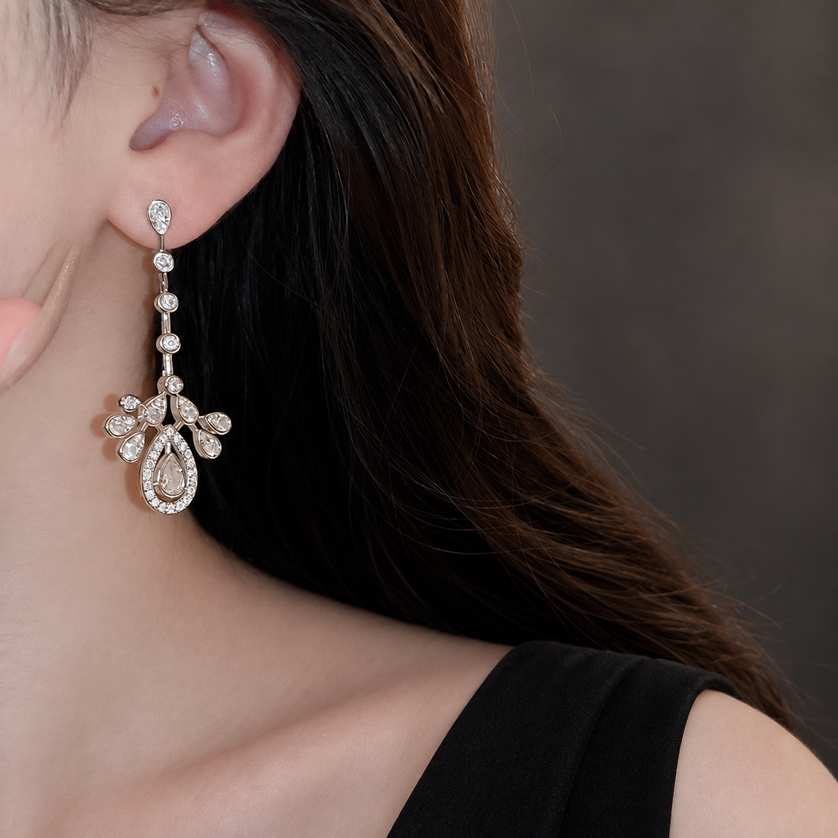 Teardrop CZ chandelier earring with four round links, styled with a black open neckline