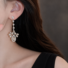 Teardrop CZ chandelier earring with four round links, styled with a black open neckline