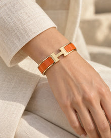 Signature H-Clasp Bangle – Minimalist & Secure Lock Bracelet, Everyday Luxury (Gold / Orange) worn on wrist with H-shaped clasp