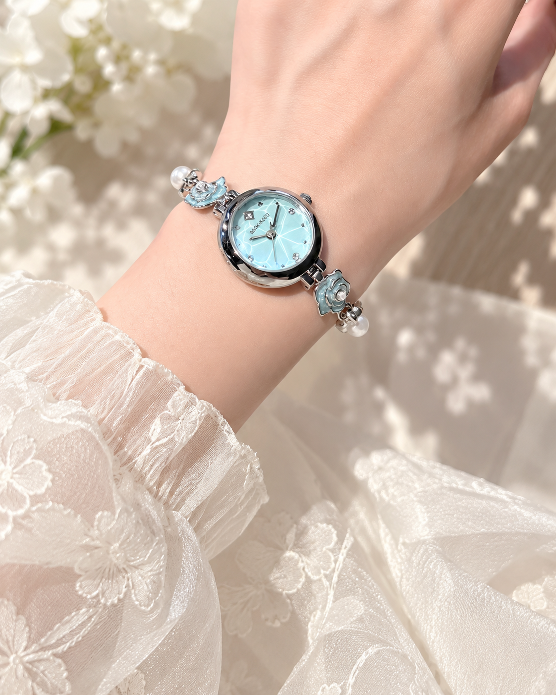 Blue camellia flower and pearl-look bracelet watch worn with an ivory blouse